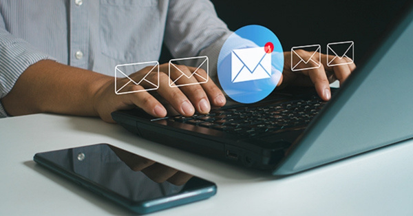 Person typing on laptop with email notifications popping up.