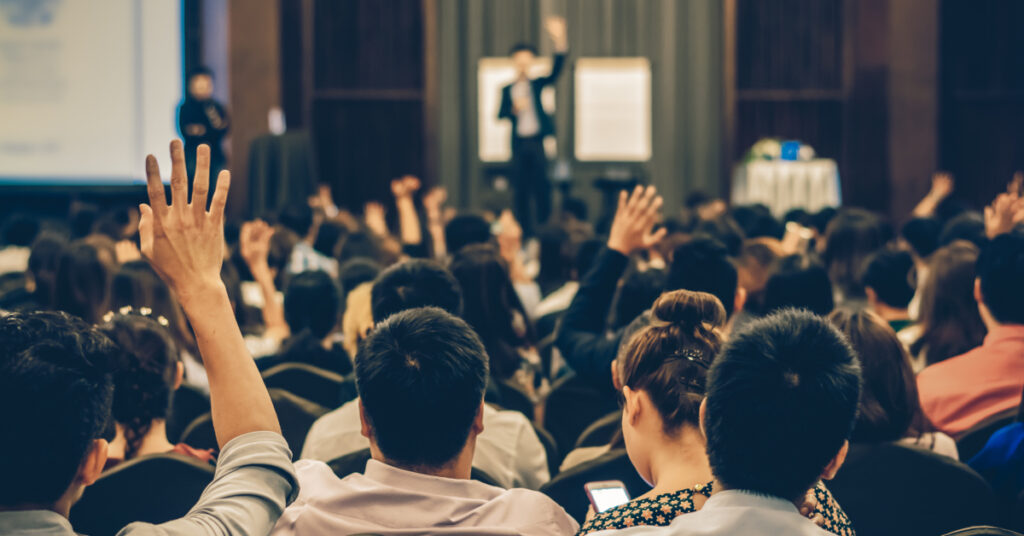 People attending a conference raise their hands.