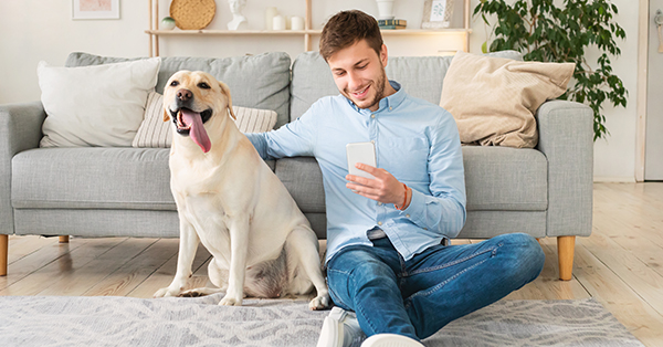 smiling man sitting on the carpet with his labrador