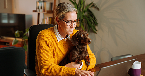woman working on laptop holding pet dog