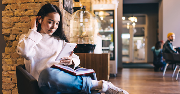 young female in headphones enjoying music and reading ebook