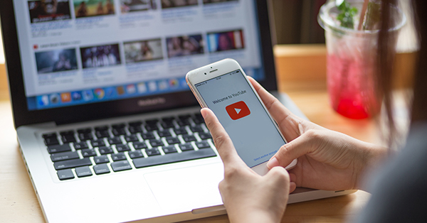 Woman holding phone with YouTube on the screen