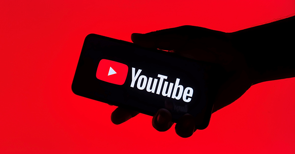 Close up view of a hand holding a mobile phone with the YouTube application displayed