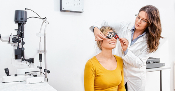 Female optometrist adjusting eye test machine for patient
