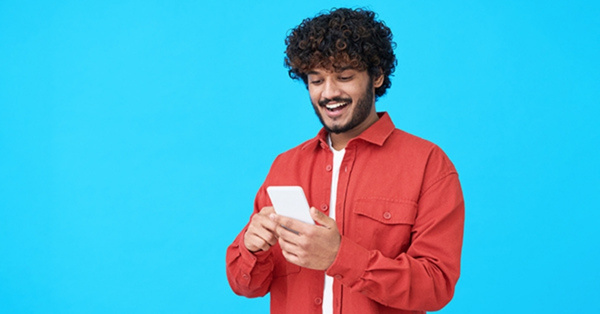 Happy young Indian man using mobile phone
