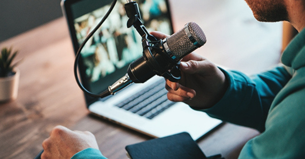 Man recording podcast with microphone and laptop