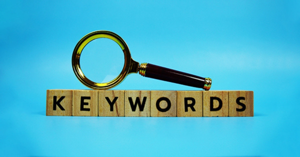 Keywords wooden blocks with magnifying glass on blue background.