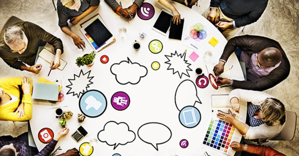 Diverse team brainstorming with colorful communication icons on table.