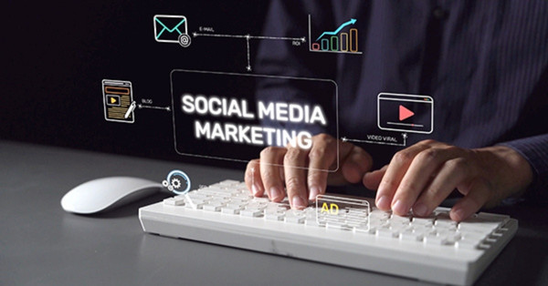 Person typing keyboard with social media marketing icons floating.
