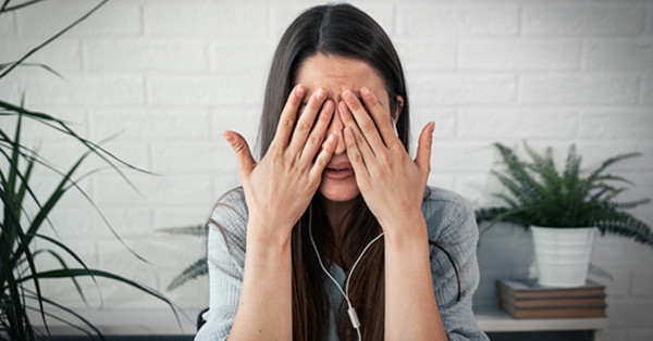 Woman covering face with hands feeling nervous on camera.