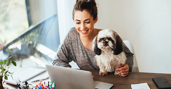 young female with a pet dog working on a laptop