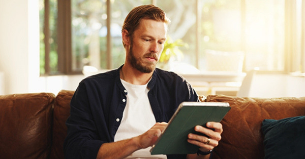 Man sitting comfortably on sofa using digital tablet