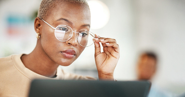 Focused woman wearing glasses working on laptop at desk